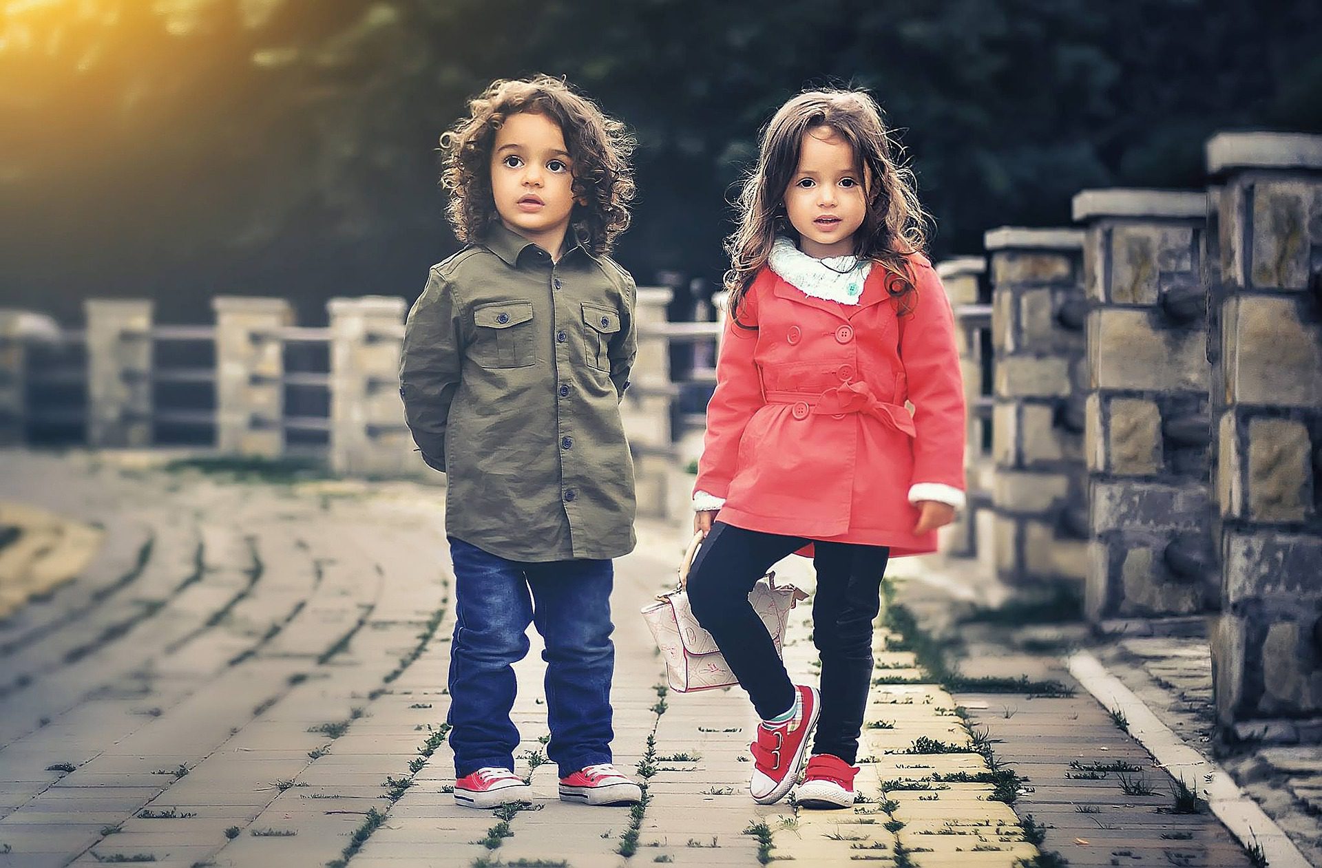 Two children standing on a brick road.