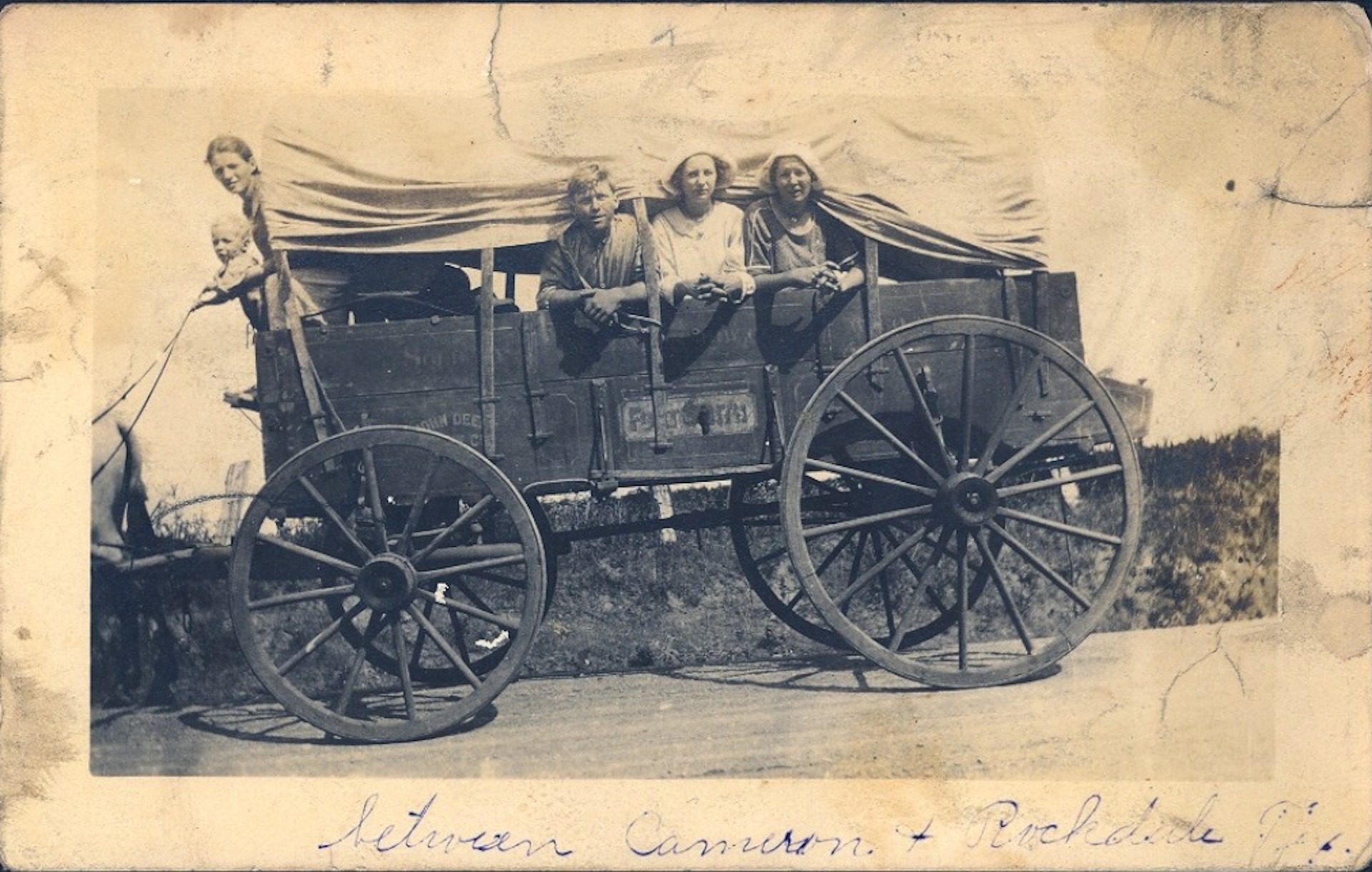 Old photo of a group of people in a covered wagon.